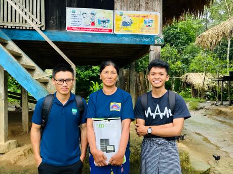 Three people smile holding a solar kit